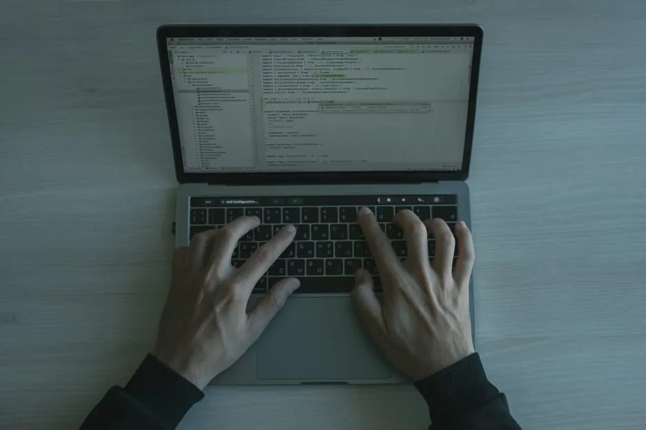 Developer typing on a laptop with code on screen, illustrating AI coding-assistant usage and billing.