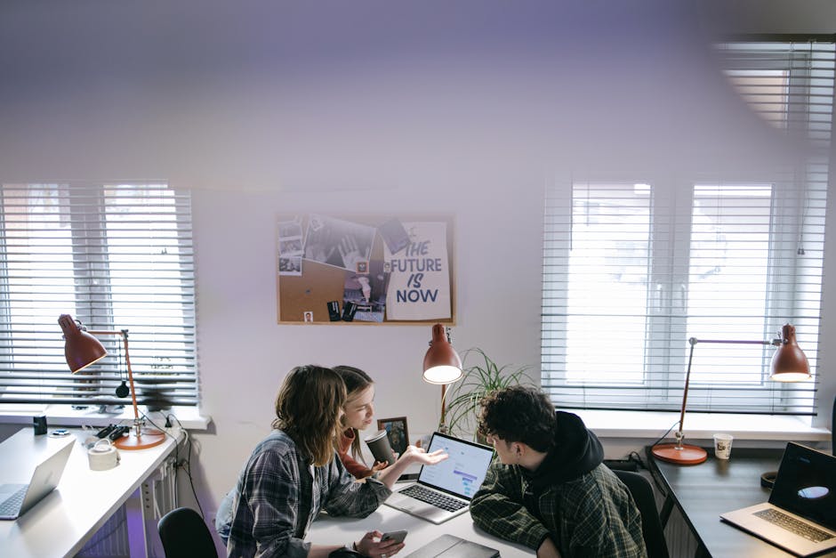 Team collaborating around a laptop with a project workspace on screen, illustrating workplace AI agents.