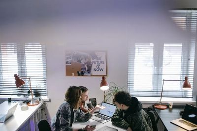 A group of people discussing ideas around laptops in a bright, modern office space.