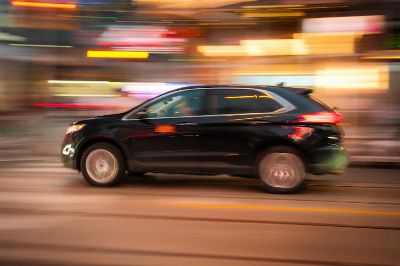 Black SUV in motion with urban background, conveying speed and city life.