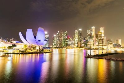Night view of Singapore's illuminated skyline and Marina Bay Sands, reflecting vibrant city lights.
