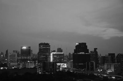 Aerial view of Bangkok's skyline in black and white captures an urban scene at dusk.