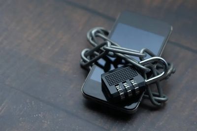 Close-up of a smartphone wrapped in a chain with a padlock, symbolizing strong security.