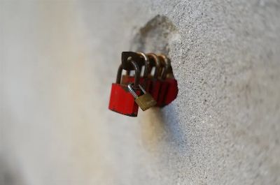 A series of red padlocks attached to a stone wall, symbolizing security and love.
