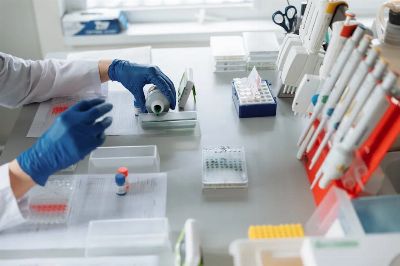 Scientist in blue gloves handling lab equipment and samples.