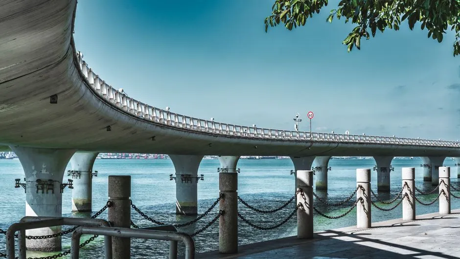 A coastal bridge crossing calm water — two retirement systems separated by one strait