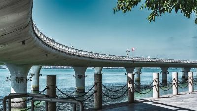 Stunning view of a modern bridge spanning across a tranquil blue river under a clear sky.