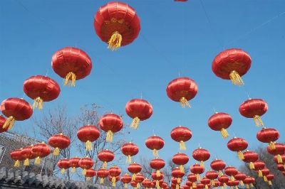 Vibrant red lanterns hanging outdoors against clear blue sky, symbolizing festive celebration.