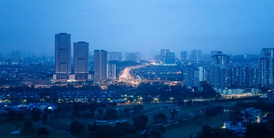 Dense Kuala Lumpur housing at blue hour, lit windows against a deep navy sky.