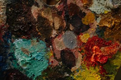 Close-up of a colorful artist's palette with various paint blobs and textures.