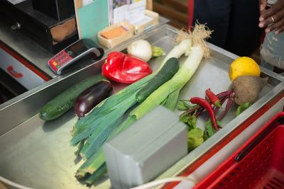 A selection of fresh vegetables on a stainless steel grocery checkout counter.