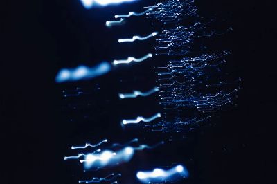Dynamic abstract photograph of blue light patterns with a dark backdrop, creating a sense of motion and mystery.