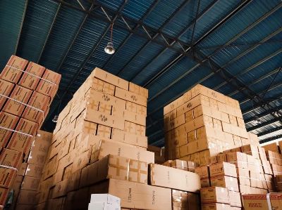 High stacks of cardboard boxes organized in a warehouse with a blue metal ceiling.