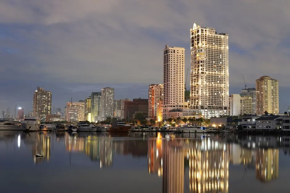 Manila skyline at twilight reflected in the bay, with high-rise towers along the waterfront