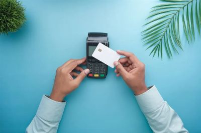 Hands using a contactless credit card on a payment terminal with a stylish minimal background.