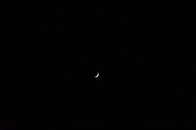 A serene crescent moon floating in a vast and dark night sky, creating a peaceful celestial scene.