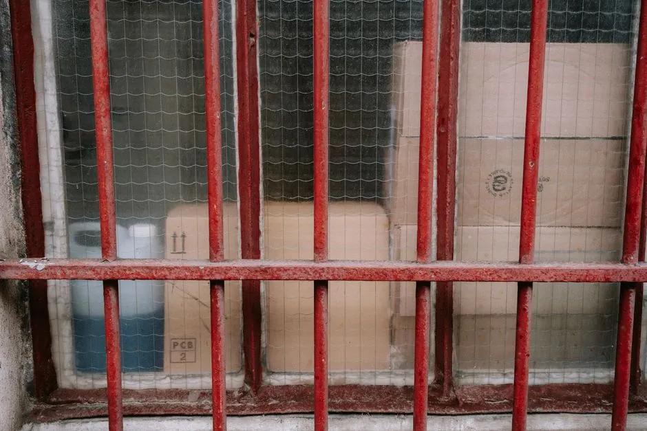 Cardboard packages stacked behind a barred window