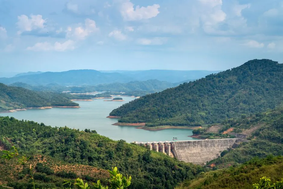 A reservoir held back by a concrete dam among forested hills