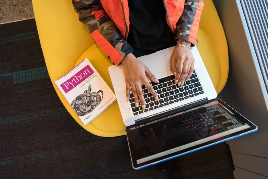 A developer typing on a laptop beside a Python programming book, the language of the affected SAP Cloud SDK