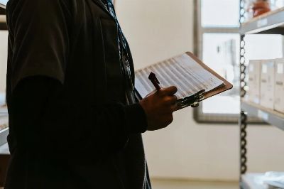 Industrial worker managing inventory in a warehouse with a clipboard and checklist.
