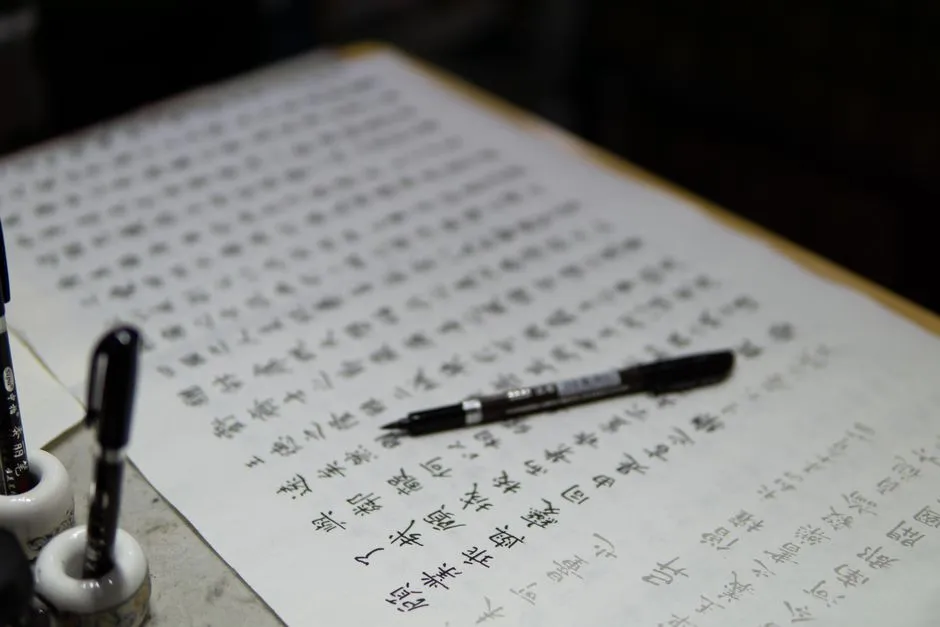 A handwritten page of Chinese characters with a pen resting on it
