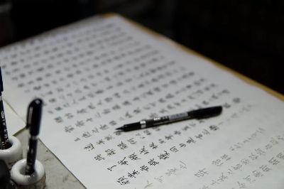 Detailed image of traditional Chinese calligraphy with ink pens and paper.
