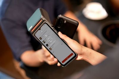 Close-up of a smartphone making a contactless payment at a modern payment terminal in a retail environment.