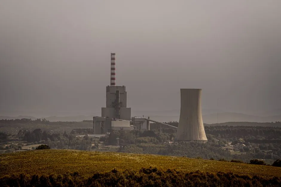 A coal-fired power station with a chimney and cooling tower in hazy air