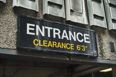 Close-up of an entrance clearance sign on a building, indicating height limit.