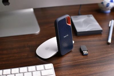 Close-up of a modern desk setup with a SanDisk external hard drive and electronics on a wooden surface.