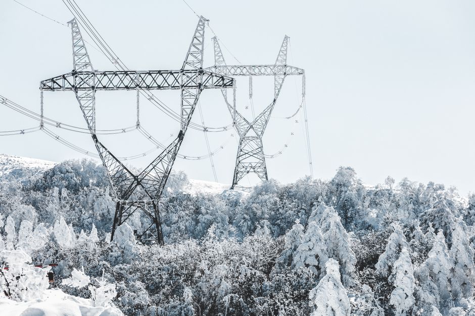 A scenic view of transmission towers amidst snow-covered trees during winter.