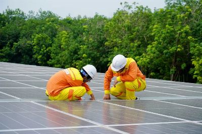 Workers installing photovoltaic solar panels on a sunny day, promoting renewable energy.