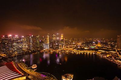 Aerial view of Singapore's illuminated skyline and waterfront at night.