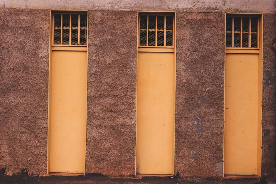 Three identical tall orange openings set in a plain earth-coloured wall