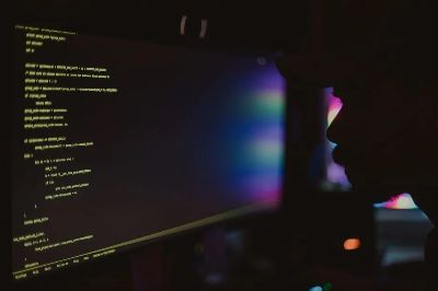 Silhouette of a programmer coding in a dark room, focusing on the screen with lines of code.