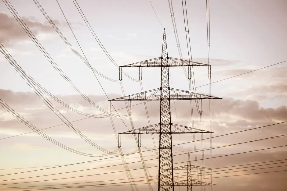An electricity transmission pylon carrying many conductors against a pale sky