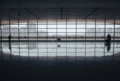 Spacious airport terminal with floor reflections, large windows, and city skyline view.