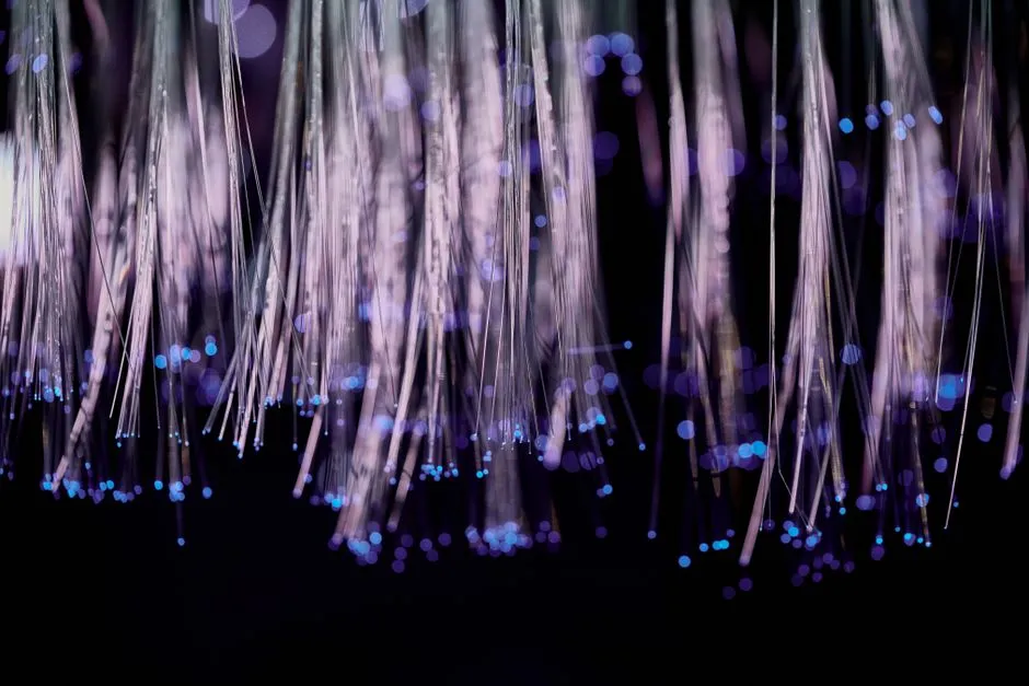 Strands of optical fibre carrying points of light against a dark background, illustrating a report on Cloudflare launching a browser built for AI agents.
