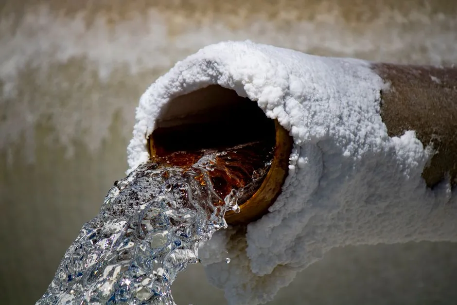 Water gushing from the open end of a pipe set in a frosted wall