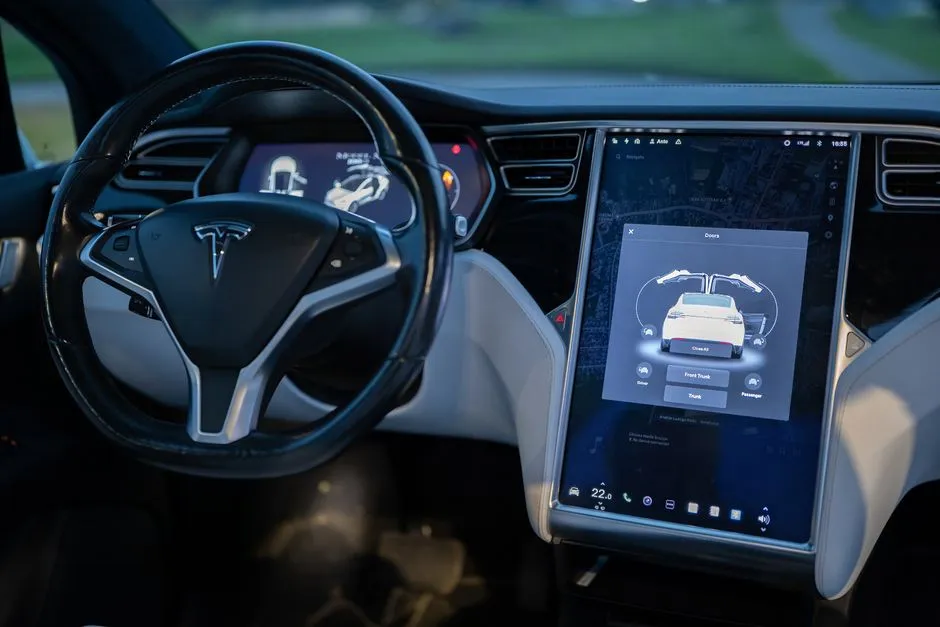 Close-up photo of a person driving a Tesla, showcasing modern vehicle interior design.