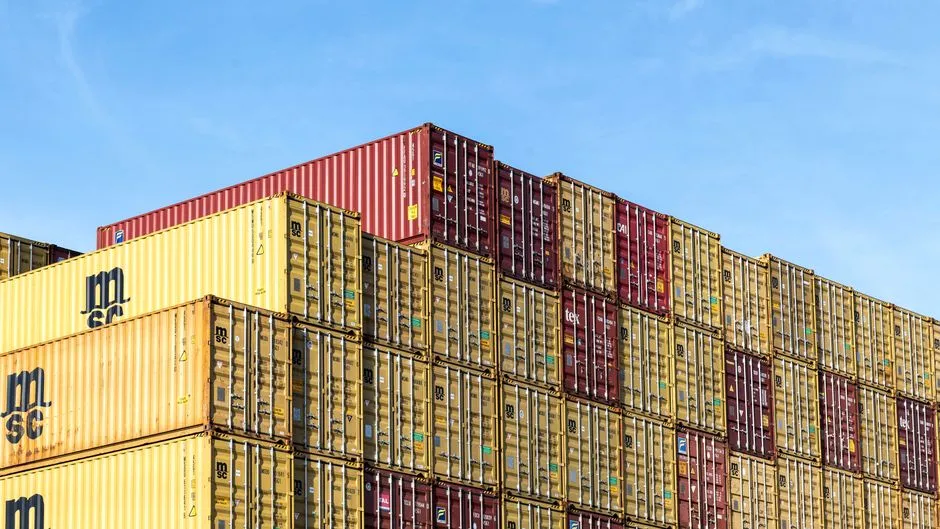 Stacked shipping containers, the metaphor software containers take their name from and the boundary the agent escaped