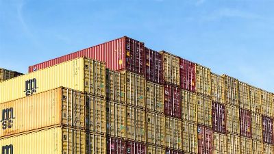 Colorful stacked cargo containers in Hamburg port under a clear blue sky.