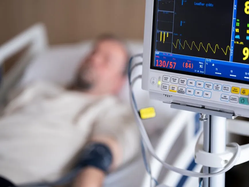 A vital signs monitor in focus beside an out-of-focus hospital bed, illustrating a report on United States state laws regulating clinical artificial intelligence.