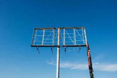 A rusty, empty billboard frame stands against a vast clear blue sky, symbolizing abandonment.