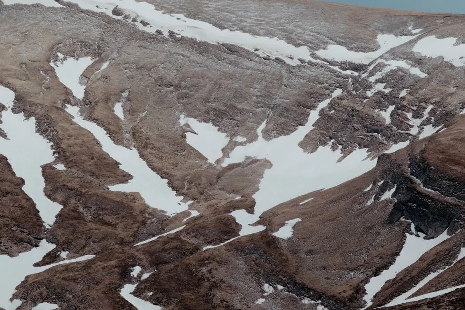 Aerial view of the snow-capped mountains in Bușteni, Romania, showcasing rugged terrain.