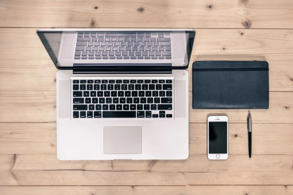 A laptop, notebook and phone on a desk, illustrating a report on venture funding flowing into tools that secure enterprise AI systems.