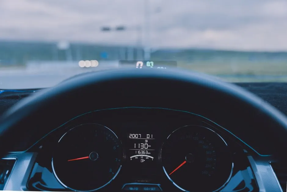 The view from a driver's seat over the steering wheel and instrument cluster to the road ahead