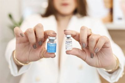 A close-up of a woman holding Xeomin and Dysport vials, showcasing cosmetic treatment options.