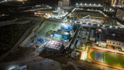 A vibrant aerial shot of a construction site at night with buildings and lights.