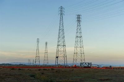 High voltage transmission towers with clear blue sky at dusk in an open field.